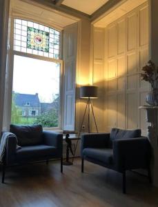 uma sala de estar com dois sofás azuis e um vitral em Statige boerderijwoning met vrij uitzicht en tuin em Hoogzand