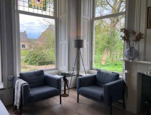 uma sala de estar com duas cadeiras e uma janela em Statige boerderijwoning met vrij uitzicht en tuin em Hoogzand