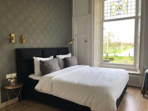 een slaapkamer met een groot wit bed en een raam bij Statige boerderijwoning met vrij uitzicht en tuin in Hoogzand