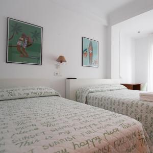 two beds in a white room with posters on the wall at Pension Angelines, Sneuu Hostel Santander in Santander