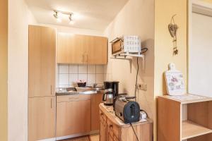 a small kitchen with wooden cabinets and a microwave at Ferienwohnung Gartenliebe in Waren