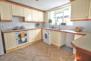 uma cozinha com armários brancos e uma máquina de lavar roupa em 4 bed home 3 mins from harbour + sandy beach em Kent