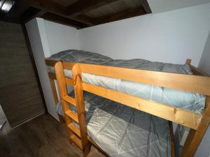 ein Etagenbett aus Holz in einem kleinen Zimmer in der Unterkunft Studio de 20m2 mansardé in La Chapelle-dʼAbondance