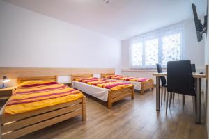 two beds in a room with a table and chairs at Ubytovna u nádraži in České Budějovice