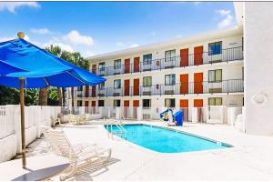 a hotel with a swimming pool and a blue umbrella at OYO Hotel Mobile, AL I-65 at Airport Blvd in Mobile