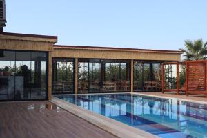 a house with a swimming pool and glass walls at Mandalin Glamping in Selçuk