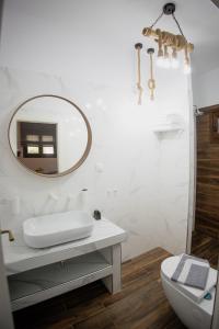 a white bathroom with a sink and a mirror at Countryside luxury studios in Káto Lekhónia