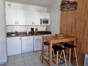 een keuken met witte kasten en een houten tafel bij Appartement T2-5 couchages L'écrin des Orres 1800 in Les Orres