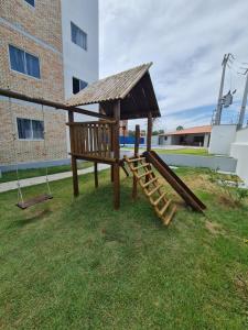 um parque infantil de madeira com um baloiço e um edifício em Apartamento aconchegante em Luis Correia em Luís Correia