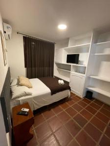 a bedroom with a bed and a tv and shelves at Pousada Ponta Mar in Natal +42 photos