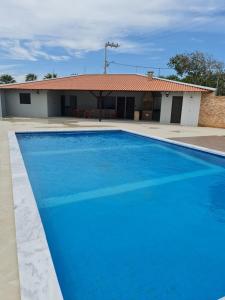 a blue swimming pool in front of a house at Apartamento aconchegante em Luis Correia in Luis Correia