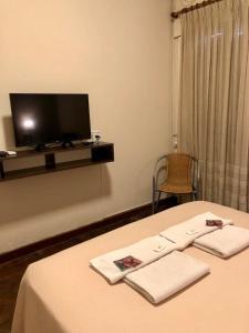 um quarto com uma cama com televisão e toalhas em Hotel Bonino em Villa Mercedes