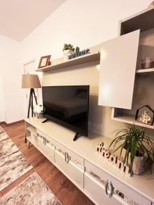 una sala de estar con TV en un centro de entretenimiento blanco en Dream apartment Gotse Delchev, en Gotse Delchev