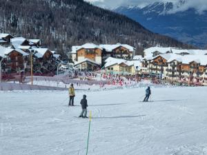 Un grupo de personas esquiando por una pendiente cubierta de nieve en Appartement T2-5 couchages L'écrin des Orres 1800, en Les Orres