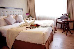 een hotelkamer met een bed met twee zwanen erop bij Aura One Hotel in Baguio
