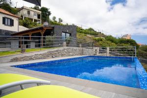 a swimming pool in front of a house at Gran Horizonte House with private pool by HR Madeira in Ribeira Brava