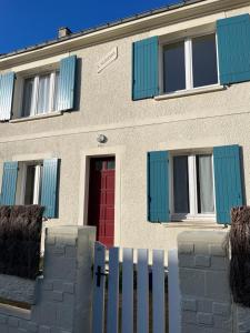une maison avec des fenêtres bleues et une porte rouge dans l'établissement Maison de caractère à 5mn à pied de la plage, à Mesquer