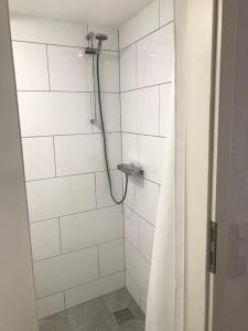 La salle de bains est pourvue d'une douche blanche avec rideau de douche. dans l'établissement Modernisiertes Gästezimmer im Ortskern, à Wehrheim