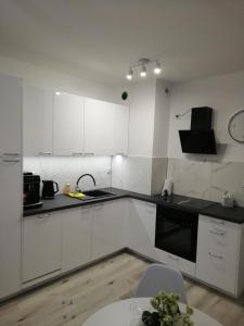 a white kitchen with white cabinets and a table at Apartament MajaHouse in Nowa Sól