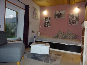 a bedroom with a bed and a couch and a window at La ferme aux chats in Formigny