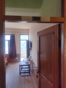 uma porta aberta para um quarto com uma mesa e um sidx de mesa em ROOP MOUNTAIN HOMESTAY em Manali