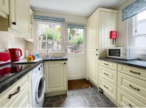 a kitchen with white cabinets and a white microwave at Waypast, Port Isaac Bay Holidays in Port Isaac