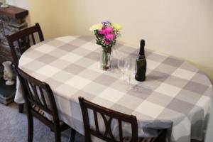 艾薩克港的住宿－Waypast, Port Isaac Bay Holidays，一张带一瓶葡萄酒和鲜花的摆在桌边的桌子