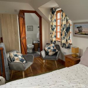 a bedroom with a bed and two chairs and a bathroom at Carraholly in Liskeard