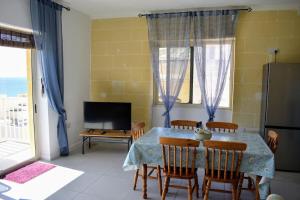 a dining room with a table and chairs and a television at Seaview 2-bedroom Apartment in Xlendi in Xlendi
