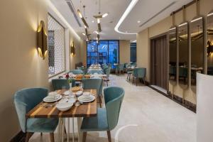 um restaurante com uma longa mesa de madeira e cadeiras azuis em Gladiolus Hotel em Jidá
