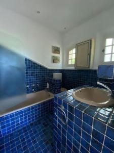 La salle de bains est pourvue de carrelage bleu, d'une baignoire et d'un lavabo. dans l'établissement Maison de Famille Les 4 Vents, à Peymeinade