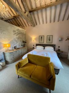 um quarto com uma cama grande e um sofá amarelo em The Lion Inn em Winchcombe