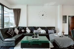 a living room with a black leather couch and a table at Onyx Stay Pool Villa @Pranburi in Ban Nong Sua