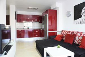 sala de estar con sofá negro y armarios rojos en South Coast Apartment, en Puertito de Güímar