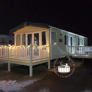 a white rv with a deck with lights on it at Bianca and marks 8 berth Caravan with Hot tub in Tattershall