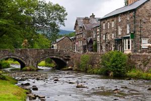 uma velha ponte de pedra sobre um rio numa cidade em The North Wales Gathering - Hot Tub & Sleeps Up To 16 em St Asaph