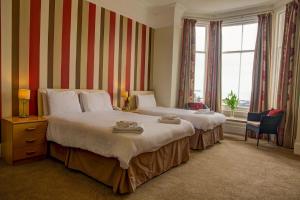 a hotel room with two beds and a window at Chatsworth House Hotel in Llandudno