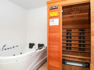 eine Badewanne im Bad mit einer Holzwand in der Unterkunft 10 person holiday home in Glesborg in Bønnerup