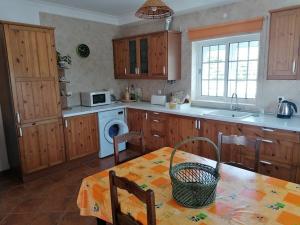 a kitchen with a table and a sink and a microwave at Casa da Carrasqueira - Sesimbra in Sesimbra +9 photos
