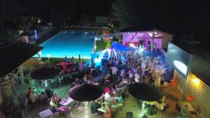 una multitud de personas sentadas alrededor de una piscina por la noche en Les hebergements Insolites, en Taradeau