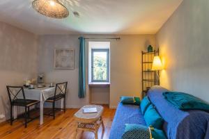 a living room with a blue couch and a table at Gîtes Un Jardin dans la Falaise in Cabrerets