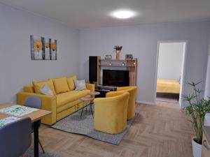 un soggiorno con divano giallo e sedie di Apartments Manna Palic a Palić