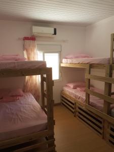 um quarto com 3 beliches e uma janela em CocoFloripa Hostel em Florianópolis