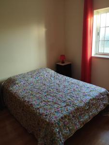 a bedroom with a bed with a floral bedspread and a window at Casa da Carrasqueira - Sesimbra in Sesimbra