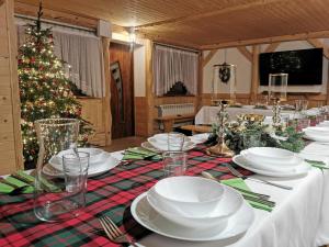 a christmas table with white dishes and a christmas tree at Gospodarstwo Agroturystyczne Baciary DOMEK W GORACH in Klikuszowa