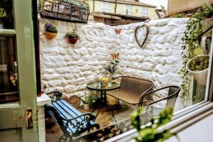 eine Terrasse mit einem Tisch, Stühlen und einer Wand in der Unterkunft Spacious Charming Cottage near Lake and Sea in Hornsea + 14 Fotos