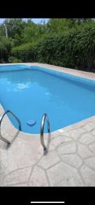 una gran piscina azul con una barandilla de metal alrededor en Casita de las sierras en Córdoba