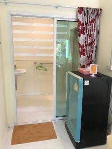 a bathroom with a shower with a refrigerator and a sink at Somrudee Resort in Nakhon Nayok