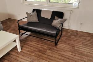 a black couch sitting in a living room with a window at Ferienunterkünfte in Sievering in Vienna