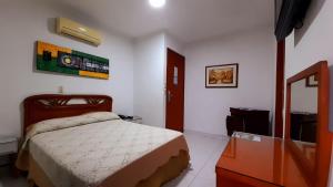 1 dormitorio con cama, tocador y espejo en Hotel Chucarima en Cúcuta